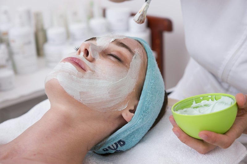 A practitioner brushing a treatment onto a client's face in a clinic