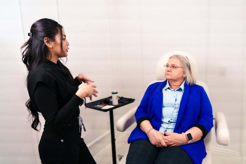 A practitioner talking with a seated client in a treatment room