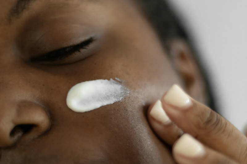 A woman smoothing moisturiser onto her cheek