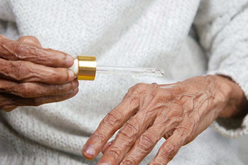 An older woman's hands holding a serum dropper